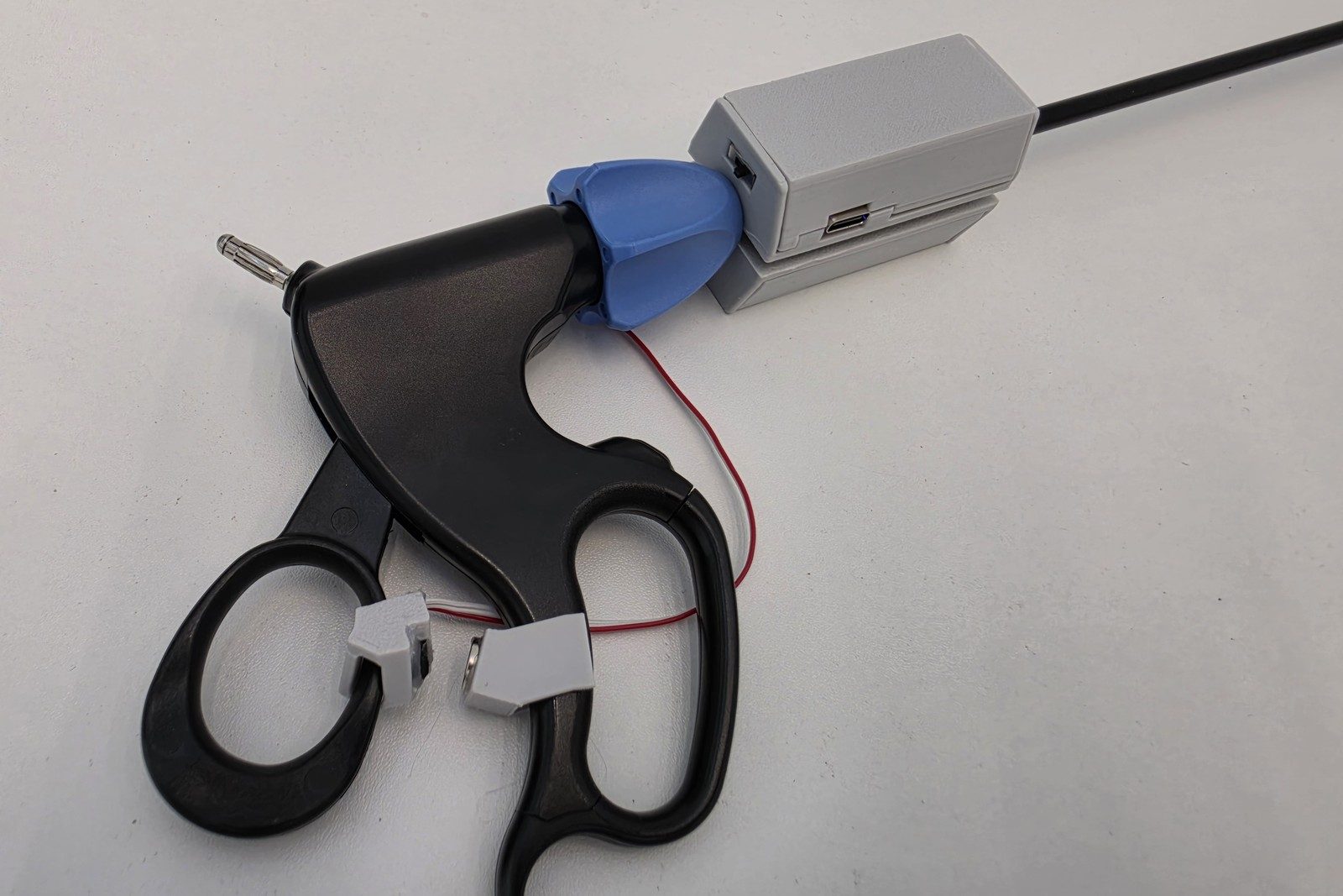 SurgiLogger clipped to the shaft of a laparoscopic grasper
